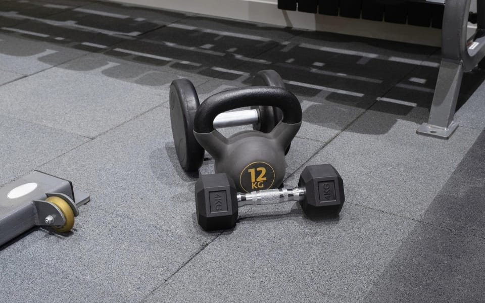 Kettlebell and dumbbells on a grey ReFlex Gym Pro tile floor