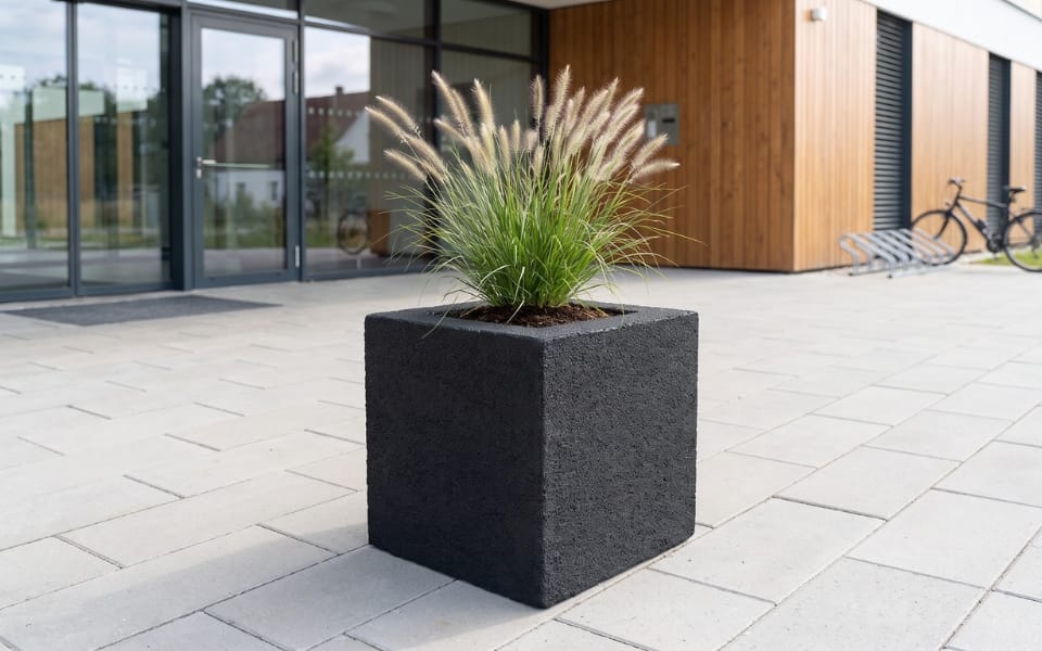 Moulded rubber planter with ornamental grass on a paved forecourt