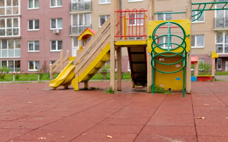 Red safety tile surface with a slide in a housing estate playground