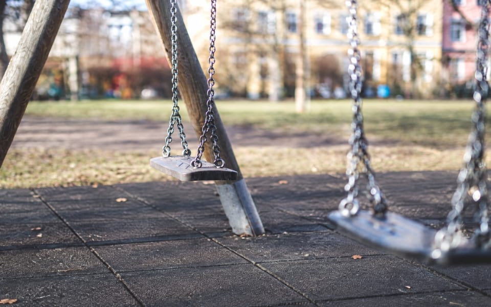Black safety tiles under a swing frame in a city park