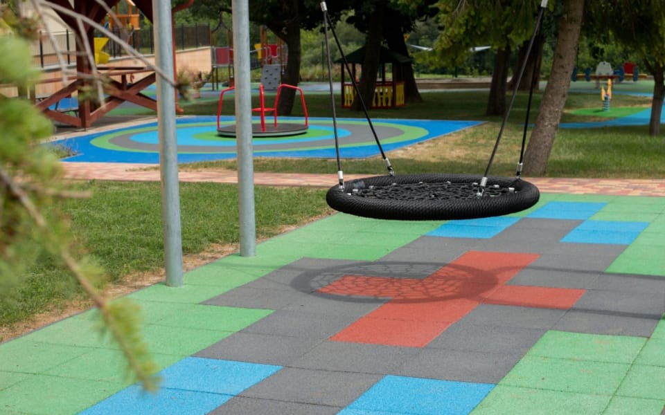 Nest swing above an EPDM tile surface patterned in green, blue and red