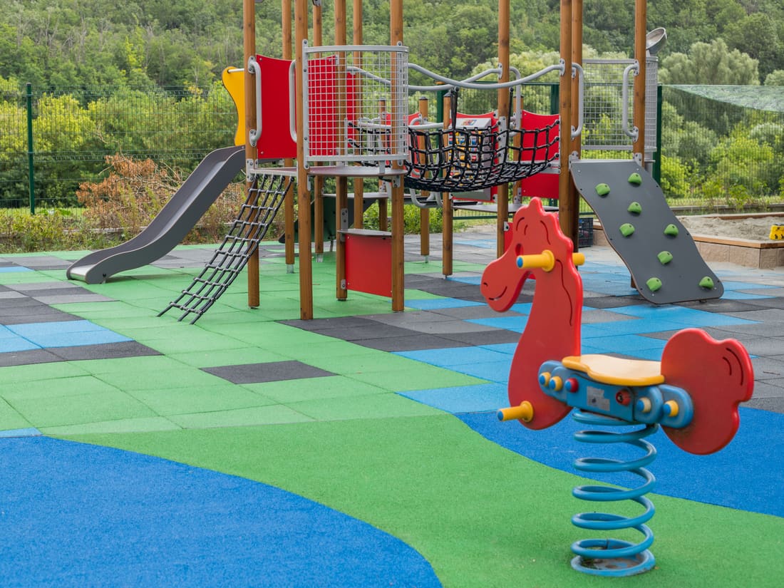 Wooden play tower with a slide on a coloured EPDM tile surface