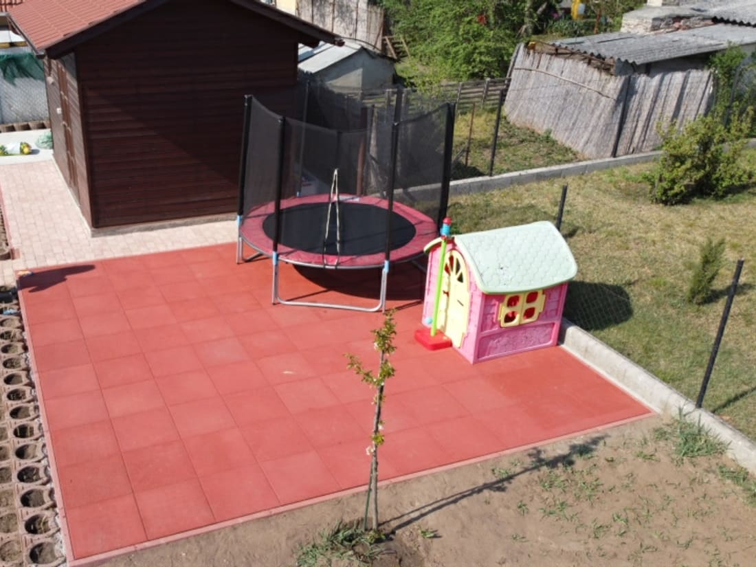 The garden rubber tile surface with the trampoline and the shed