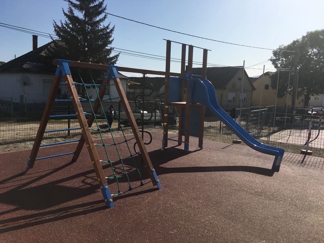 Wooden climbing frame with a blue slide on red rubber tiles