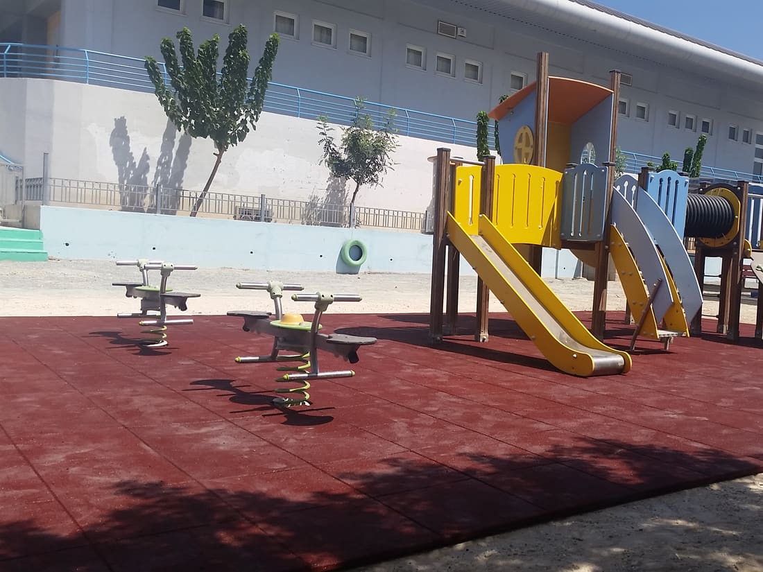 School playground with a slide on red rubber tiles