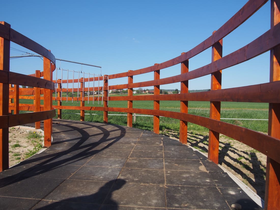 Horse walker with a rubber tile floor and a timber fence