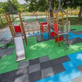 Colourful rubber safety tiles across a playground with climbing frames and springers